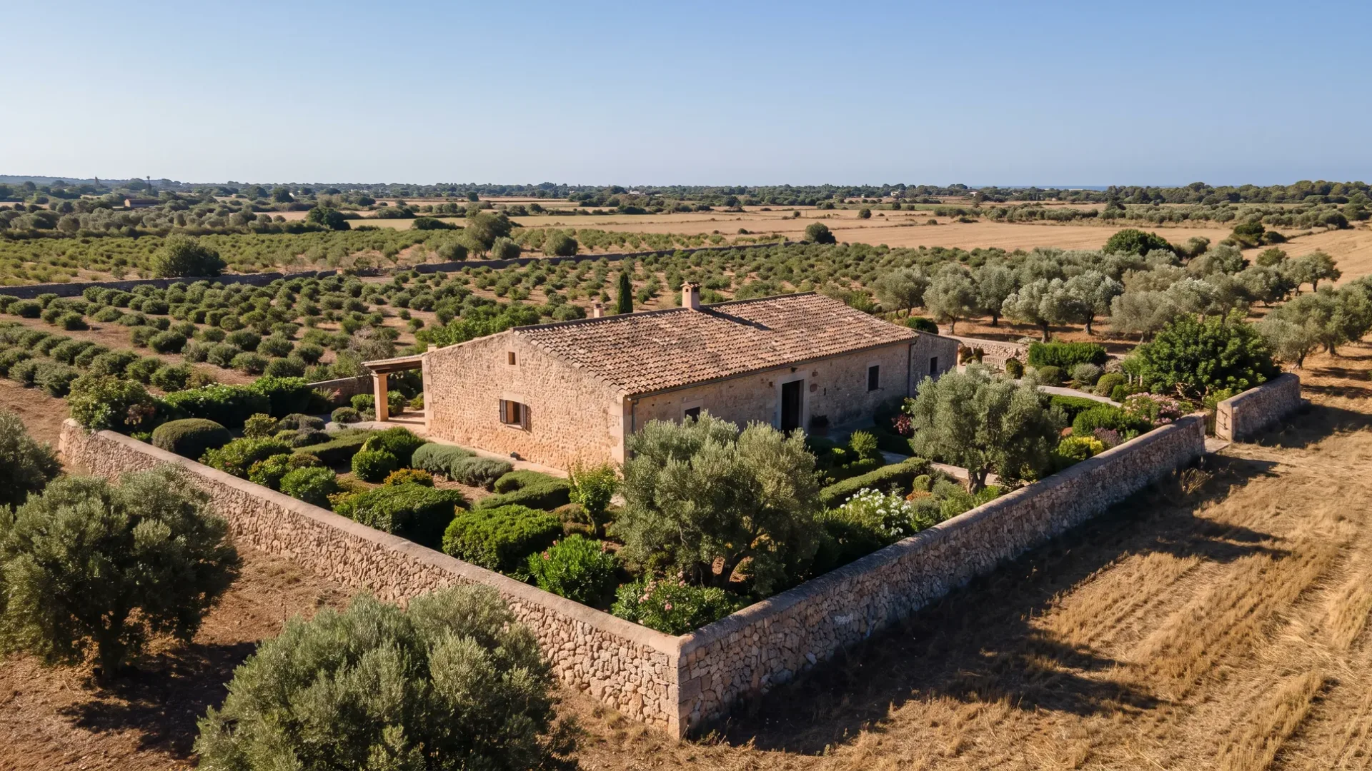 A walled garden enclosure around a stone farmhouse at Llubí, with caper and almond land running out flat beyond
