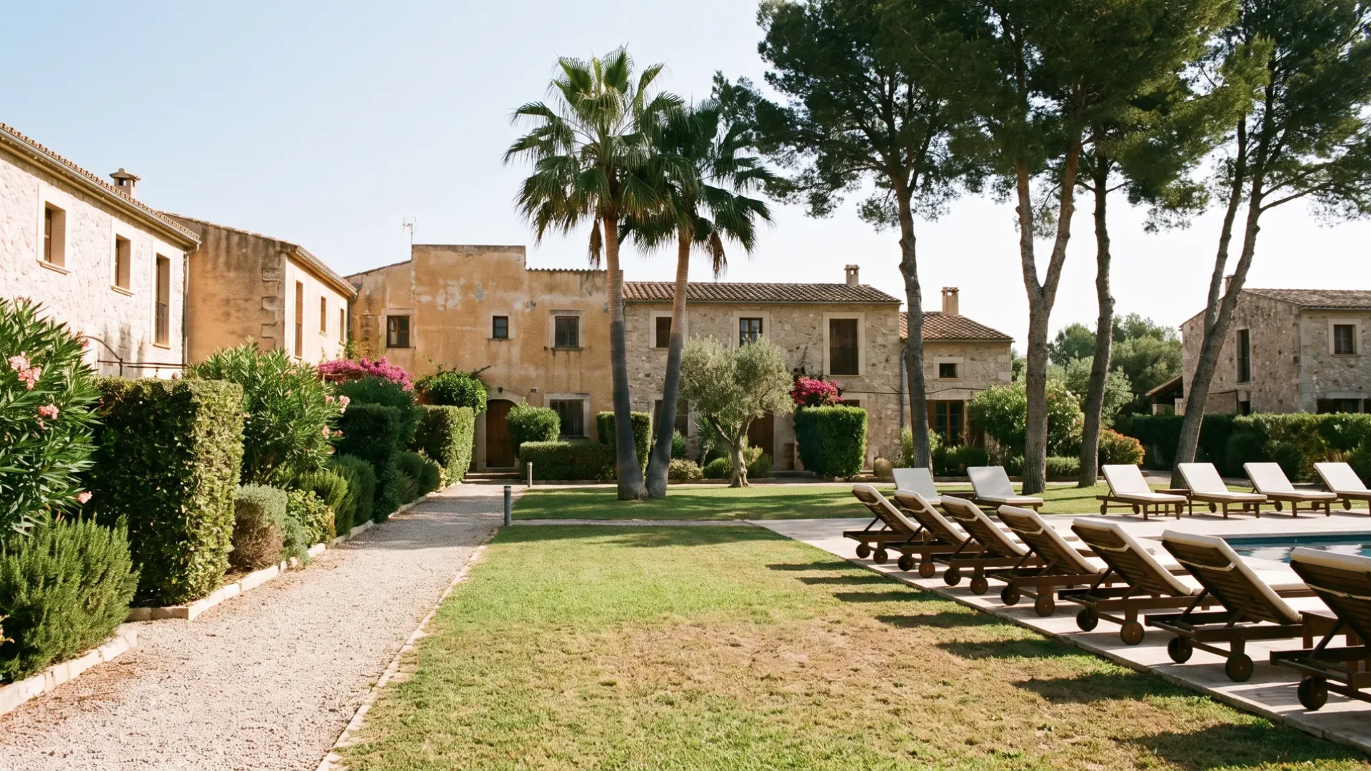 Shared grounds of a Mallorcan residential community, with clipped hedging, a communal lawn and a line of loungers